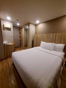 a bedroom with a large white bed with a wooden headboard at Baan Tanwa - MRT Ratchadapisek Exit 1 or 2 in Bangkok