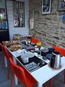 a white table with red chairs and a table with food on it at La Longère d'Arzoù Chambres D'hôtes in Mériadec