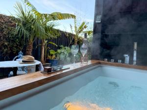 a hot tub in a backyard with wine glasses and bottles at The Cabana Luxury Award Winning Tiny Home with Hot Tub and Private Garden 2 mins Walk to Ryde Beach in Ryde +30 photos