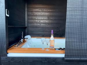 a bath tub with a bottle of alcohol and two wine glasses at The Cabana Luxury Award Winning Tiny Home with Hot Tub and Private Garden 2 mins Walk to Ryde Beach in Ryde