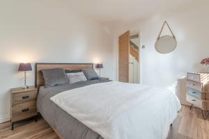 een witte slaapkamer met een groot bed en een spiegel bij Ty-Mari in Harlech