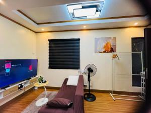 a living room with a couch and a tv at H&K Guest House in Urdaneta