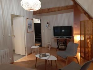a living room with a television and a table at La Longère d'Arzoù Chambres D'hôtes in Mériadec