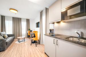 a kitchen and living room with a couch and a table at Hine Adon Avenches A2 Hotel Aparthotel with Tea room - Self Checkin in Avenches