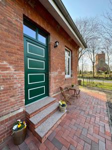 una casa de ladrillo con una puerta verde y un banco en Heuler beim Ochsenturm am Deich, 