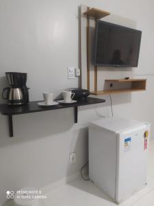 einen Tisch mit zwei Tassen und einen TV an der Wand in der Unterkunft Suíte praia dos Anjos in Arraial do Cabo