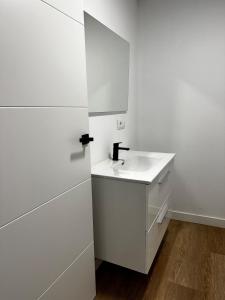 a white bathroom with a sink and a mirror at A Casiña da Ponte in Lugo