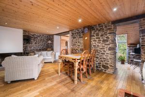 ein Esszimmer mit einem Tisch und einer Steinwand in der Unterkunft Gîte du 17 - sauna jacuzzi hammam in Trans