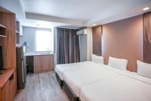 Una habitación de hotel con dos camas y un televisor. en Baan Tanwa - MRT Ratchadapisek Exit 1 or 2, en Bangkok