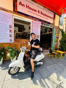 a man sitting on a scooter in front of a store at An house Ninh Binh in Ninh Binh