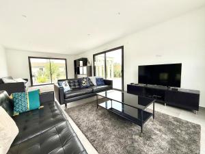 a living room with a couch and a flat screen tv at Villa Amara Piscine 7 personnes in Mios
