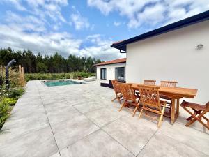 a patio with a wooden table and chairs and a pool at Villa Amara Piscine 7 personnes in Mios
