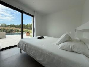 a bedroom with a white bed and a large window at Villa Amara Piscine 7 personnes in Mios +24 photos