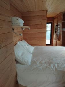 a bedroom with a white bed in a wooden wall at Bateau Lac du Der - Nuisement - Navigation 