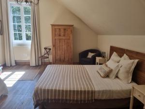 a bedroom with a bed and a chair and a window at Ferme de l'Abbaye in Dury