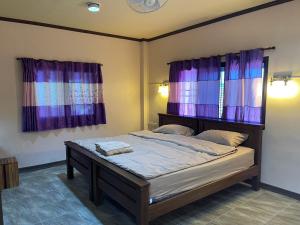 een slaapkamer met een bed met paarse gordijnen bij Stay here at pai in Pai