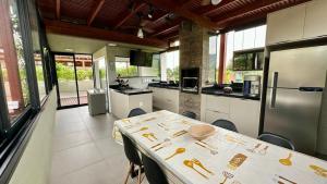 a large kitchen with a table and a refrigerator at Casa Nova em Maresias in São Sebastião
