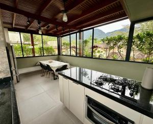 a kitchen with a view of a table and a dining room at Casa Nova em Maresias in São Sebastião