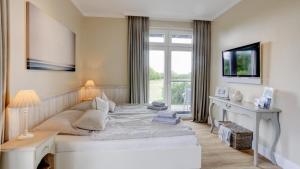 una camera da letto con un grande letto bianco e una finestra di Strandresidenz Vogelflug Meerblick Fehmarnsund a Fehmarnsund