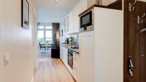 una cucina con armadi bianchi e una TV a parete di Strandresidenz Vogelflug Meerblick Fehmarnsund a Fehmarnsund Altre 18 foto