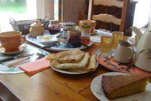 a wooden table topped with plates of bread and jam at Chambres D'hôtes d'Evelyne in Sainte Anne d'Auray 