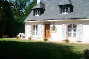 a white house with a brown door and a yard at Chambres D'hôtes d'Evelyne in Sainte Anne d'Auray  +10 photos