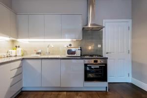a kitchen with white cabinets and a sink and a microwave at Sandy Bay - Mins To Margate Main Sands in Margate +20 photos