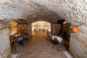 a room with a stone wall and a table and chairs at Royal Cave Noszvaj in Noszvaj