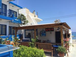 Un pequeño restaurante con una pérgola de madera en el lateral de un edificio. en Anastasia Studios And Suites, en Vrachonisída touArchangélou