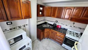 a kitchen with wooden cabinets and a white stove top oven at Hermoso Departamento Completo en PB in Río Grande