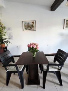 a dining room table with a vase of flowers on it at Confort INN in Otopeni