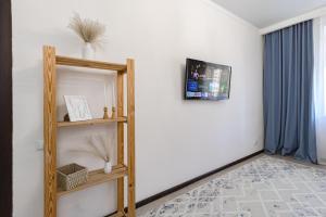 Zimmer mit einem Regal und einem TV an der Wand in der Unterkunft Апартаменты в ЖК Ирина рядом с Баянтау in Pawlodar + 9 Fotos