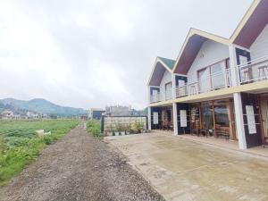 a house on a dirt road next to a field at Dieng Indah Villa & Cabin by Hello Room in Dieng
