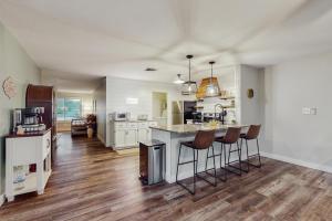 una cocina con armarios blancos y una isla con taburetes. en Tempe Comfort Haven, en Tempe