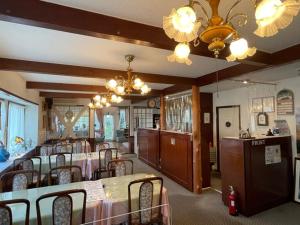 a restaurant with tables and chairs and a chandelier at ペンションあけまの森 in Daisen