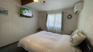 a bedroom with a white bed and a tv on the wall at ペンションあけまの森 in Daisen +24 photos