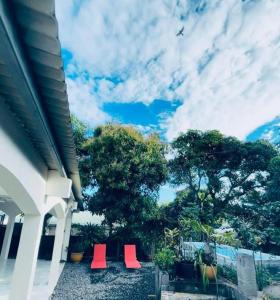 two red chairs sitting outside of a house at Cilaos Gite le Cryptomeria o693-70-59 79 in Saint-Leu