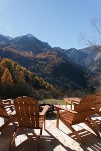 two chairs and a picnic table on a deck with mountains at Appartements au Cerf de la Lune in Crots