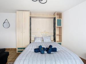 a bedroom with a bed with blue slippers on it at Les Cerisiers in Saint-Étienne-de-Crossey