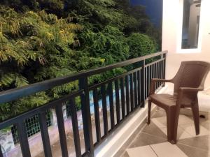 a chair on a balcony with a wall of trees at Mount Bliss Stay in Tiruvannāmalai