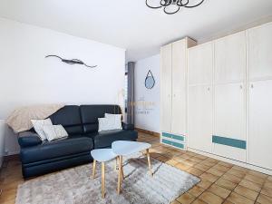 a living room with a black couch and a table at Les Cerisiers in Saint-Étienne-de-Crossey