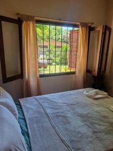 Un dormitorio con una cama y una ventana con vistas. en Chalet con puerta al arroyo, en Villa General Belgrano 1 foto más