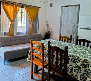 Una sala de estar con una mesa y sillas y un sofá. en Chalet con puerta al arroyo, en Villa General Belgrano