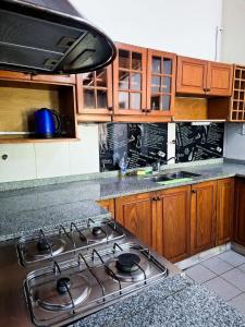 Una cocina con estufa y gabinetes de madera. en Chalet con puerta al arroyo, en Villa General Belgrano