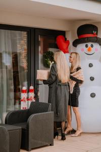 deux femmes debout devant un bonhomme de neige dans l'établissement Domki Balticana, à Władysławowo