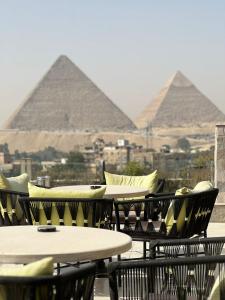 un grupo de mesas y sillas con pirámides en el fondo en Comfort Giza View, en El Cairo