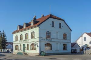 a white building with a red roof on a street at Hotel Forchhammer in Pliening
