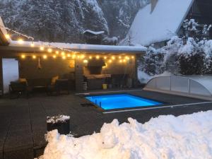 a house with a swimming pool in the snow at Chata Čaks in Nižný Klátov