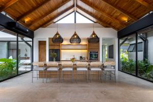 an open kitchen with a bar with stools at Villa Bahia Oceanview Designer Retreat Malpais in Mal País