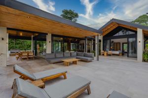 an outdoor patio with couches and tables and windows at Villa Bahia Oceanview Designer Retreat Malpais in Mal País
